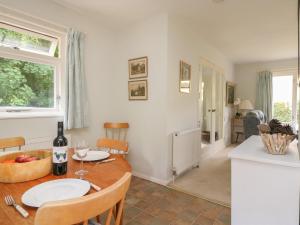 a kitchen and dining room with a table with a bottle of wine at Woodlands Cottage in Dorchester