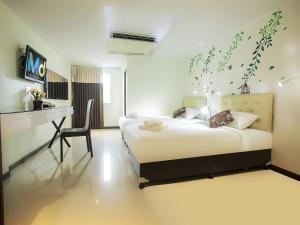 ein Schlafzimmer mit einem Bett und einem Schreibtisch mit einem Stuhl in der Unterkunft MD Grand Hotel Nakhon in Nakhon Si Thammarat
