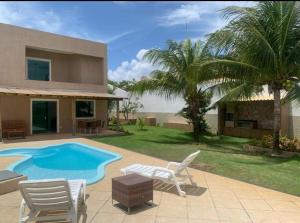 una casa con piscina e due sedie a sdraio di Excelente casa com Piscina a Camaçari