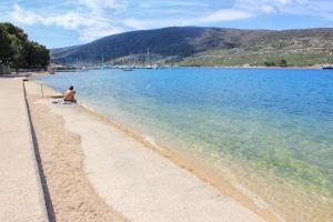 a man sitting on a beach next to the water at Apartments with a parking space Cres - 7985 in Cres