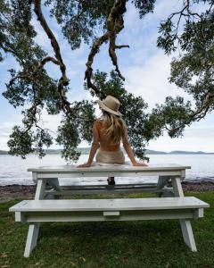 a woman sitting on a picnic table by the water at Tiona Holiday Park in Tiona