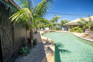 a swimming pool with a palm tree next to a house at Tiona Holiday Park in Tiona