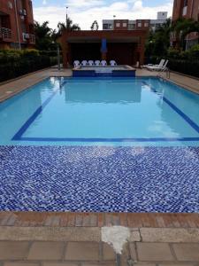 a large blue swimming pool with chairs in a building at Habitación excelente ubicación sur y servicio de parqueadero in Cali