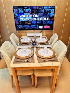 - une table avec des chaises et une télévision dans la chambre dans l'établissement Stylish 1 Bedroom Condo Unit with Perfect Pool View Balcony at Fame Residences, à Manille