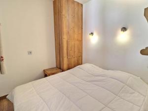 a bedroom with a white bed and a wooden door at Appartement La Tania, 2 pièces, 4 personnes - FR-1-182A-23 in Courchevel