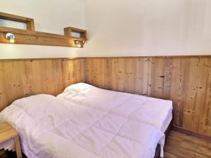 łóżko w pokoju z drewnianymi panelami w obiekcie Appartement La Tania - 4 pers, skis aux pieds, balcon, proche commodités - FR-1-182A-24 w Courchevel