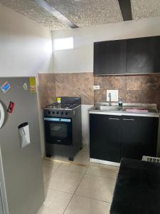 een keuken met een zwarte kachel en een wastafel bij Apartamento CERCA AEROPUERTO, Fotos y huellas para visa americana, embajada EEUU in Bogota