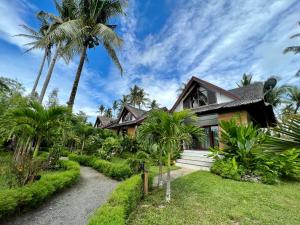 a house with palm trees in front of it at The Village Siargao in General Luna