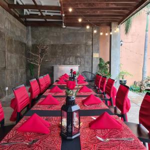 una mesa larga con servilletas rojas y sillas rojas en North Tourist Inn en Bacolod