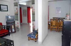 a living room with a table and chairs and a tv at Marry House in Dhaka