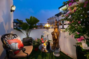 een balkon met een standbeeld van een vrouw en bloemen bij Hanoi Garden Hotel & Spa in Hanoi