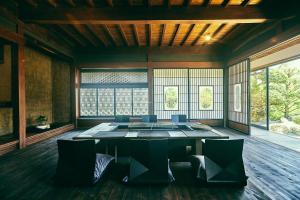 una sala da pranzo con tavolo, sedie e finestre di 古民家宿るうふ 丘之家 Okanoie a Yamanashi
