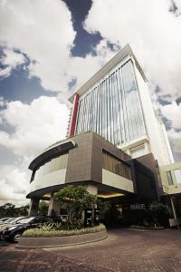 een groot gebouw met auto's geparkeerd voor het bij The Premiere Hotel Pekanbaru in Pekanbaru