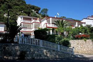 a large white house on a hill with a fence at Apartments by the sea Supetarska Draga - Gornja, Rab - 2016 in Supetarska Draga