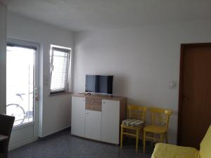 a living room with a tv on a cabinet and two chairs at Apartments by the sea Supetarska Draga - Gornja, Rab - 2016 in Supetarska Draga
