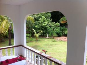 een kamer met een balkon met uitzicht op een tuin bij Dan Kazou Self Catering in La Digue