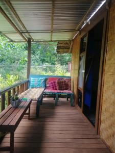 a wooden porch with a bench and a television at Genevieve Guest House and Tours in Siquijor