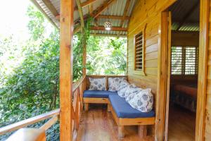 un porche de una cabaña de madera con un banco azul en EL GALLO ECOLODGE, en San Felipe de Puerto Plata