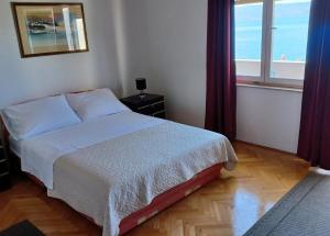 um quarto com uma cama e uma grande janela em Apartments Mari - 40 m from sea em Krilo