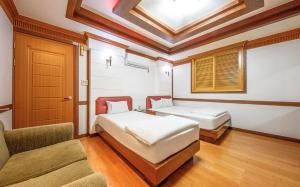 a bedroom with two beds and a couch and a window at Utopia Hotel in Gumi
