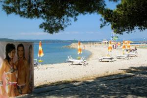 Una foto de una pareja en una playa con sombrillas en Apartments by the sea Crikvenica - 16970 en Crikvenica