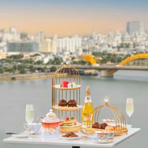 a table with two cakes and pastries in bird cages at HAIAN Riverfront Hotel Da Nang in Da Nang