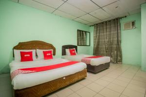 2 łóżka w pokoju z zielonymi ścianami i czerwonymi poduszkami w obiekcie OYO 90124 Payang Puri Baru Hotel w mieście Sarikei