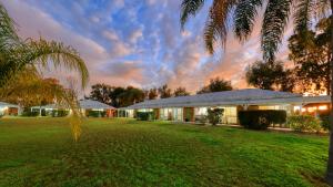 a house with a green lawn in front of a building at Chinchilla Great Western Motor Inn in Chinchilla