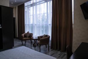 una habitación de hotel con una ventana con sillas y una mesa en Belon Lux Hotel en Astaná