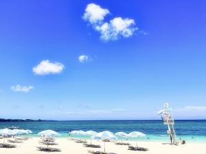 a beach with chairs and umbrellas and the ocean at Pension Moon Villa in Onna
