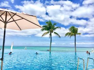 a swimming pool with palm trees and the ocean at Pension Moon Villa in Onna