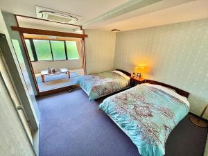 two beds in a room with a window at Pension Moon Villa in Onna +30 photos