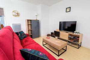uma sala de estar com um sofá vermelho e uma televisão de ecrã plano em Les jardins de Rangueil, Parking, Métro, Piscine em Toulouse