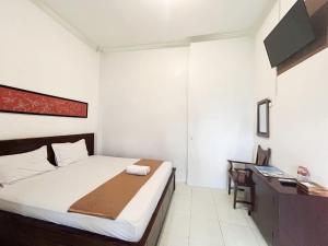 a small bedroom with a bed and a desk at Indonesia Hotel Malioboro in Yogyakarta