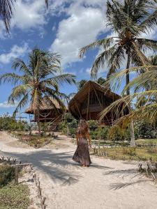 a little girl walking on a beach with palm trees at Villa Sabiá - Eco Bungalows in Prea