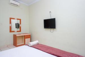 a bedroom with a bed and a tv on the wall at Urbanview Hotel Platinum Parepare in Parepare