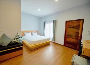 a bedroom with a white bed and a wooden door at Intha Resort in Ban Khao Lao