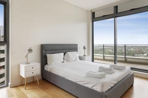 a bedroom with a large bed with a large window at KULA Macquarie Park in Sydney