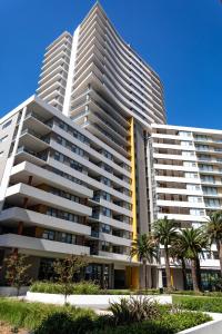 a large apartment building with palm trees in front of it at KULA Macquarie Park in Sydney