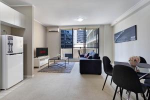 a kitchen and living room with a couch and a tv at KULA North Sydney-Napier in Sydney