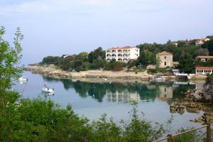 un petit bateau dans une rivière avec des maisons sur une colline dans l'établissement Apartments with parking space Potocnica, Pag - 4096, à Stara Novalja