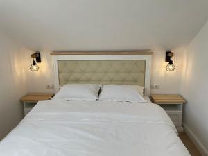 um quarto com uma grande cama branca e 2 luzes em Chic Studio Maramures em Vişeu de Sus