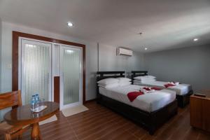 um quarto de hotel com duas camas e uma mesa em One Averee Bay Hotel em Coron