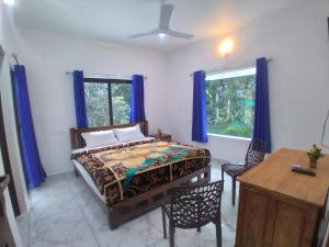 a bedroom with a bed and a table and two windows at WinterHome homestay in Munnar