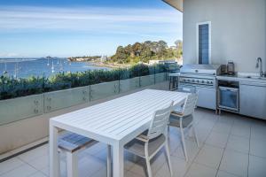 een keuken met een witte tafel en uitzicht op het water bij Penthouse On The Promenade in Batemans Bay