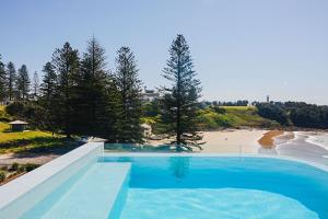 a swimming pool with a view of a beach at The Surf Yamba in Yamba