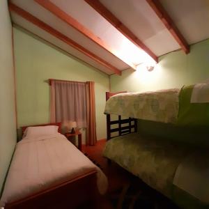 a small bedroom with two beds and a window at Cabañas El Portal in Neltume