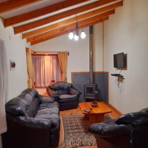 a living room with leather couches and a tv at Cabañas El Portal in Neltume