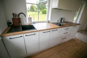 a kitchen with white cabinets and a sink and a window at Arčiau Gamtos Virinta in Kurkliai +7 photos