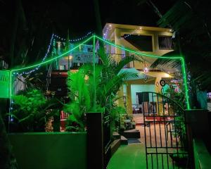 a building with green lights in a yard with plants at Luciano Guest House in Arambol